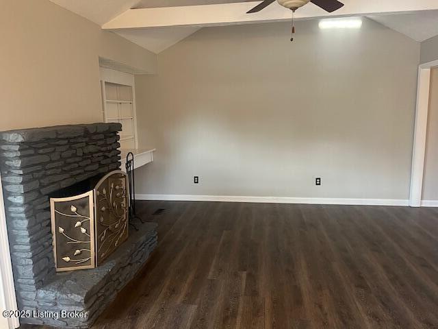 unfurnished living room featuring baseboards, ceiling fan, vaulted ceiling, a stone fireplace, and wood finished floors