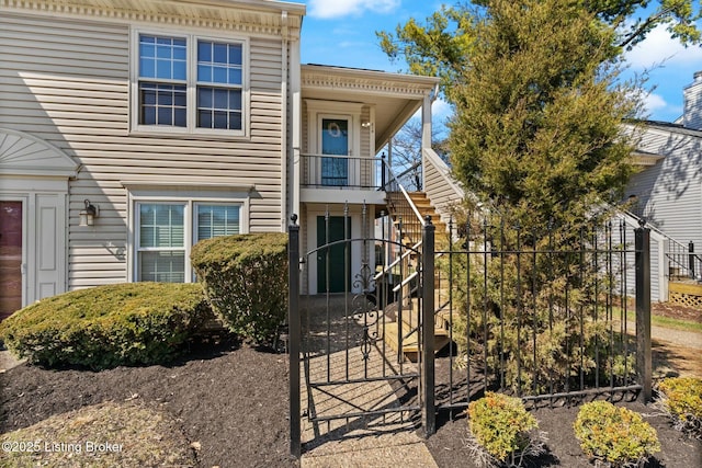 exterior space with stairway, a fenced front yard, and a gate