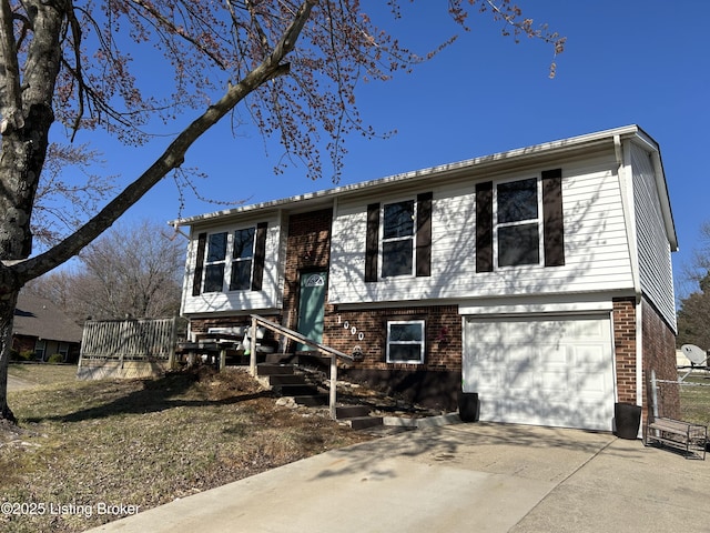 bi-level home featuring entry steps, an attached garage, brick siding, and driveway