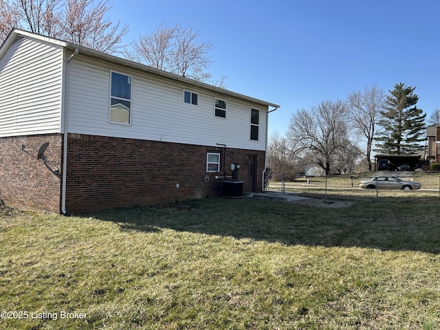 back of property with brick siding, central air condition unit, a lawn, and fence