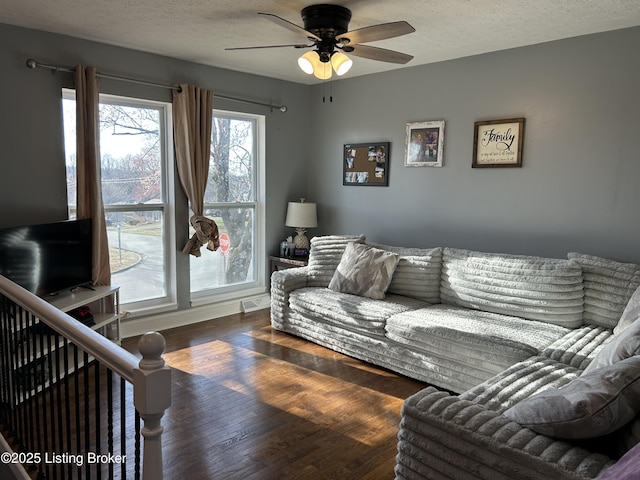 living room with ceiling fan, wood finished floors, and a textured ceiling