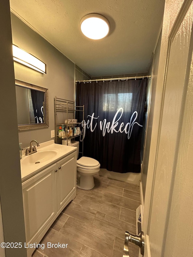 bathroom with vanity, a textured ceiling, toilet, and wood finish floors