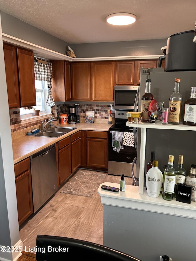 kitchen featuring a sink, stainless steel appliances, tasteful backsplash, and light countertops