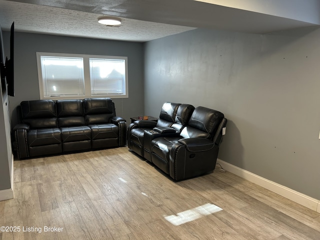 living area featuring a textured ceiling, baseboards, and wood finished floors