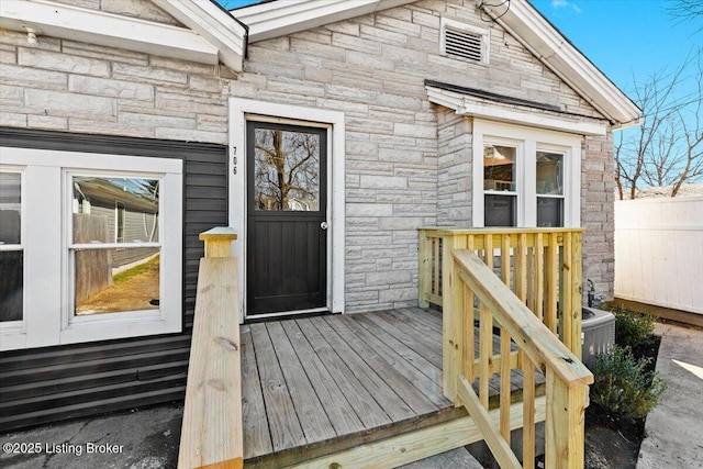 doorway to property featuring fence and stone siding