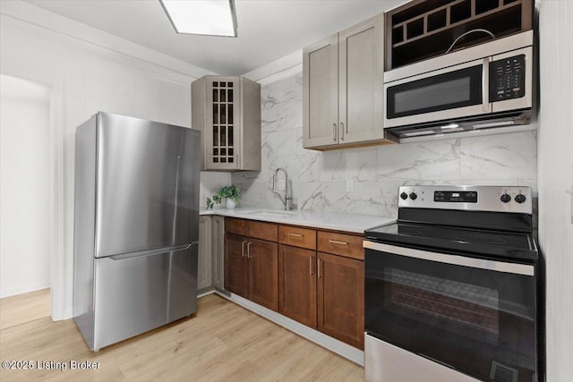 kitchen featuring a sink, stainless steel appliances, backsplash, and light countertops