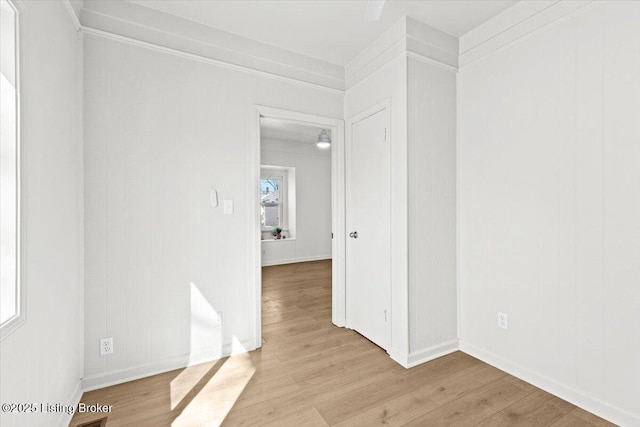 unfurnished room with baseboards, light wood-style flooring, and ornamental molding