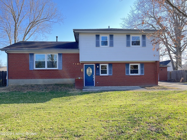 tri-level home featuring a front yard, fence, and brick siding