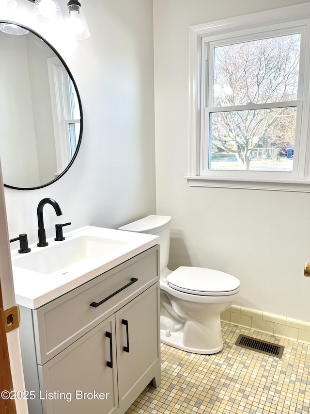 half bath featuring visible vents, toilet, vanity, and tile patterned flooring