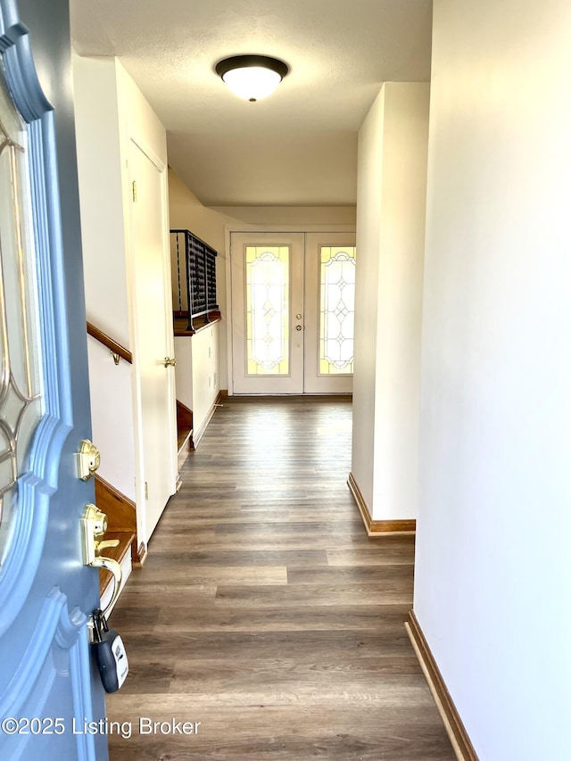 hall featuring baseboards, stairs, french doors, wood finished floors, and a textured ceiling