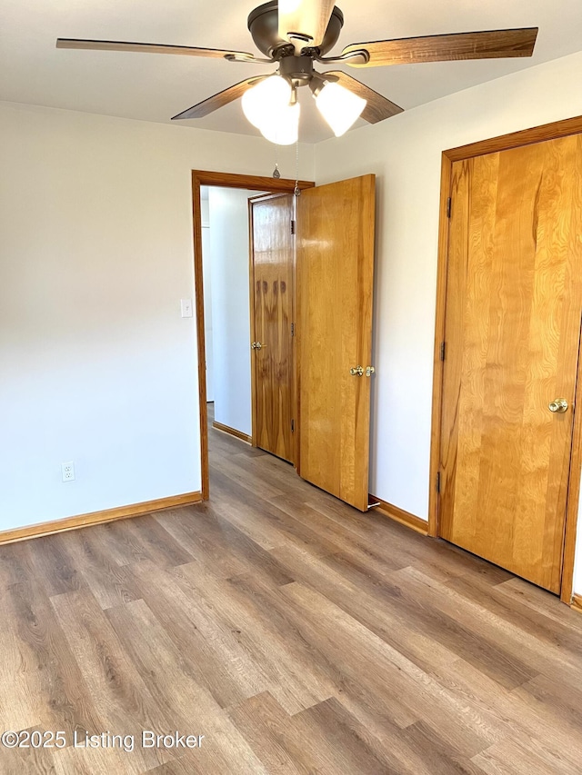 unfurnished bedroom with ceiling fan, baseboards, and wood finished floors