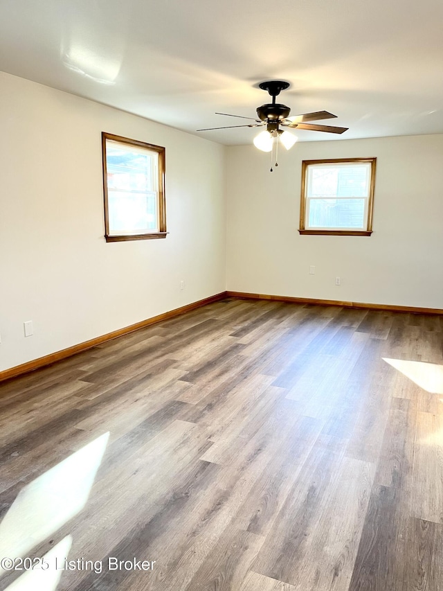 empty room featuring baseboards, wood finished floors, and a ceiling fan