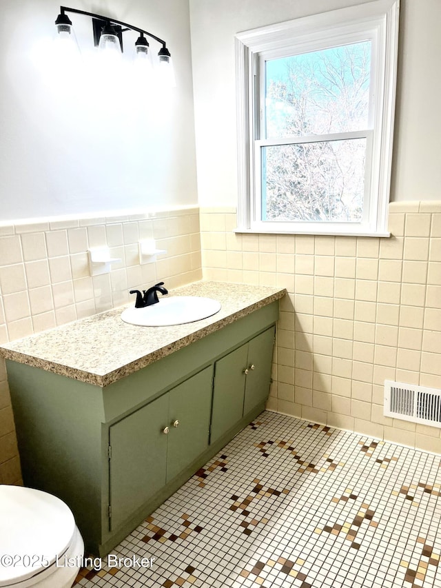 bathroom featuring tile patterned flooring, tile walls, vanity, and visible vents