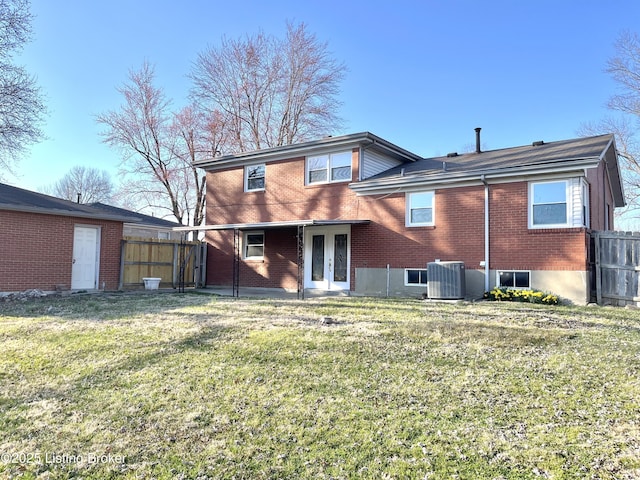 back of property featuring cooling unit, fence, brick siding, and a lawn