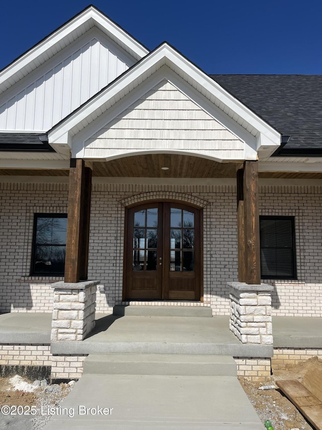 doorway to property featuring a porch, french doors, and brick siding