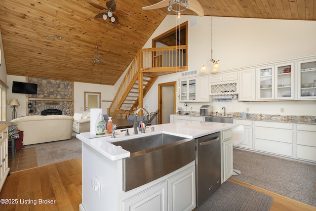 kitchen with a ceiling fan, a fireplace, a sink, dishwasher, and wooden ceiling