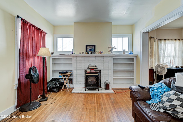 living room with a wealth of natural light, a wood stove, baseboards, and hardwood / wood-style flooring