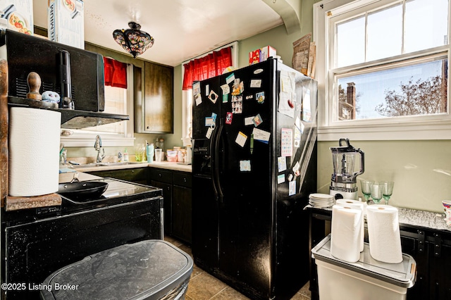 kitchen featuring a sink, light countertops, light tile patterned floors, black appliances, and dark cabinets