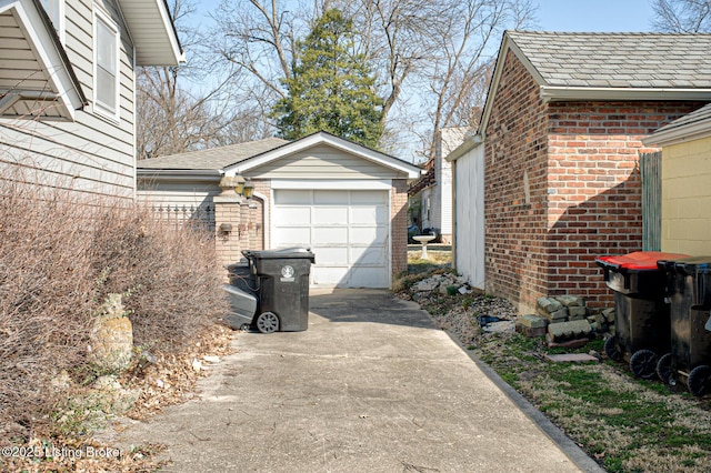 view of side of property with an outdoor structure, a garage, brick siding, and driveway