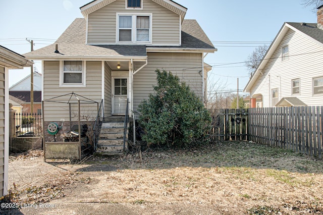 view of front of home featuring a fenced backyard and a shingled roof