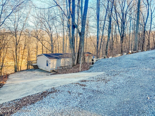 exterior space featuring a view of trees and gravel driveway