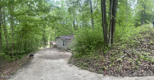 exterior space featuring a view of trees and driveway