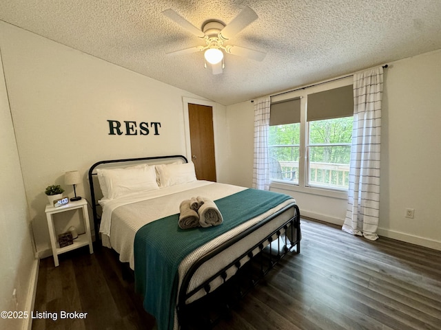 bedroom featuring dark wood-type flooring, baseboards, vaulted ceiling, a textured ceiling, and a ceiling fan