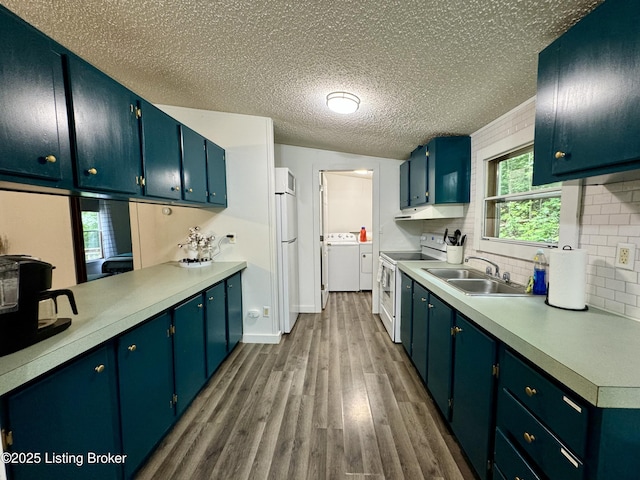 kitchen featuring a sink, washing machine and dryer, white appliances, light countertops, and dark wood-style flooring