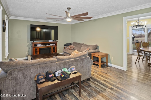 living area with ceiling fan with notable chandelier, a textured ceiling, wood finished floors, crown molding, and baseboards