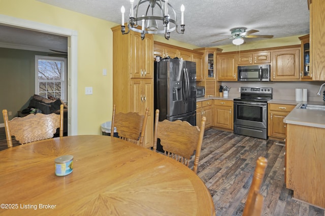 kitchen with ceiling fan with notable chandelier, a sink, dark wood finished floors, stainless steel appliances, and light countertops