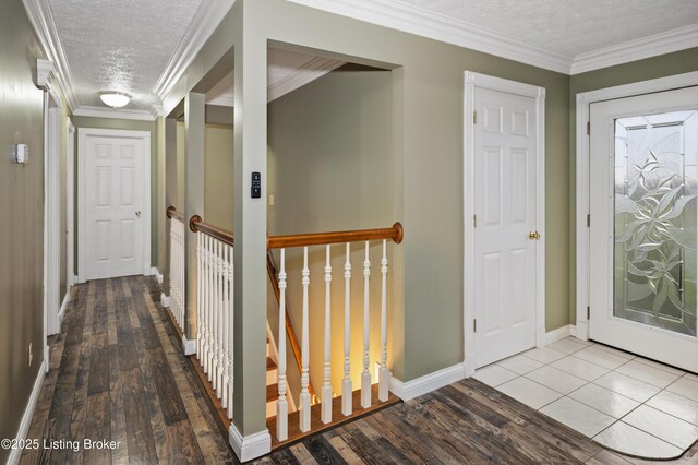 corridor with wood finished floors, a textured ceiling, and ornamental molding