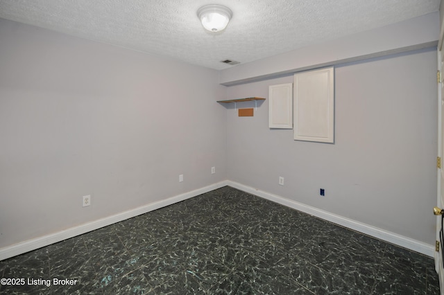 empty room with visible vents, baseboards, dark floors, and a textured ceiling