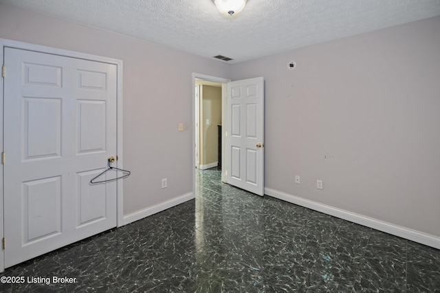 unfurnished bedroom with tile patterned floors, visible vents, baseboards, and a textured ceiling