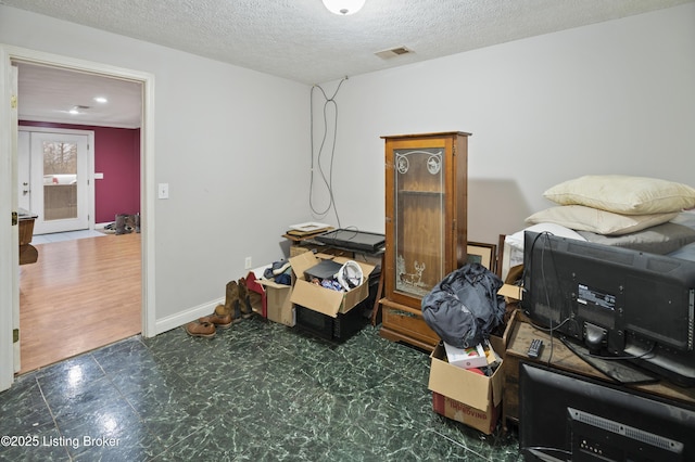 interior space with tile patterned floors, baseboards, visible vents, and a textured ceiling