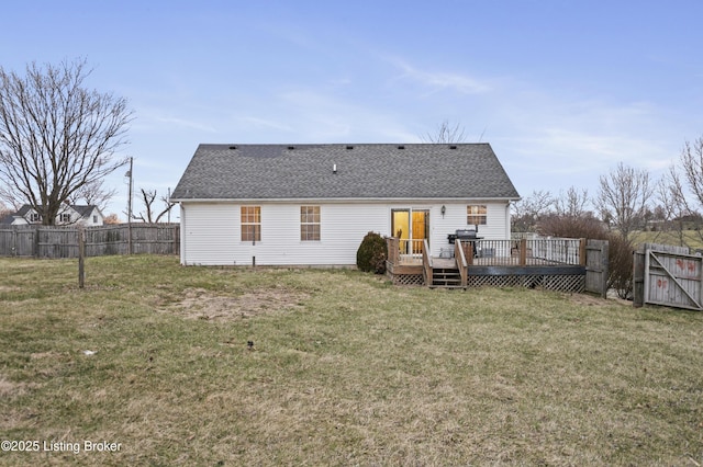 rear view of property with a fenced backyard, a deck, a shingled roof, and a yard