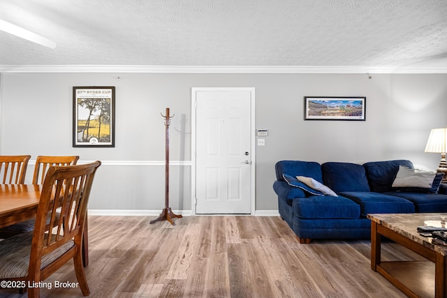 living area with baseboards, a textured ceiling, wood finished floors, and crown molding