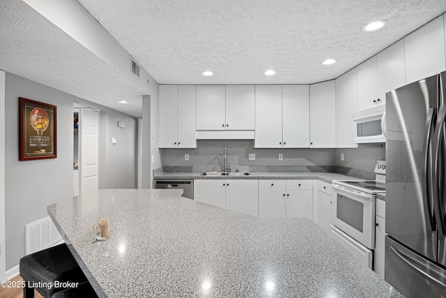 kitchen featuring visible vents, a textured ceiling, stainless steel appliances, and a sink