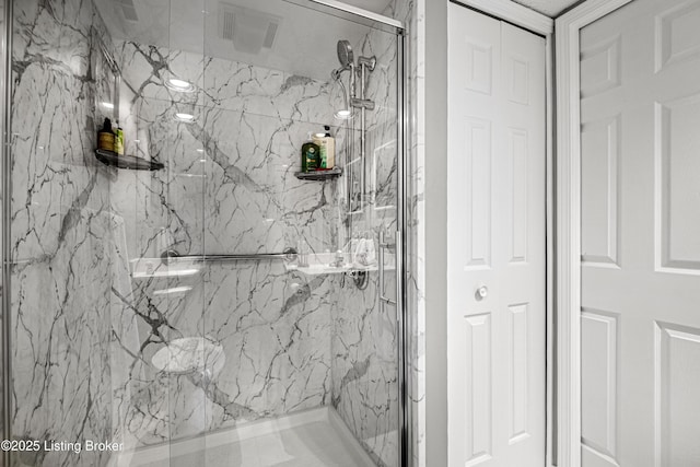 bathroom featuring a marble finish shower