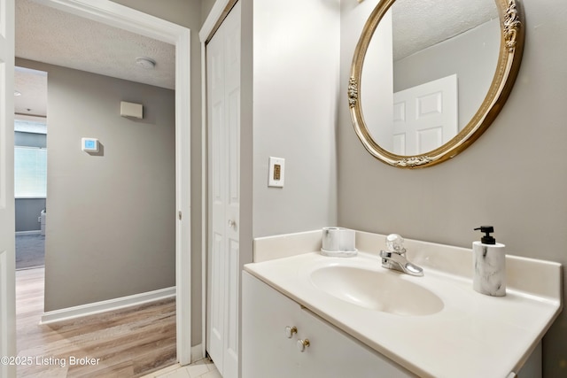 bathroom featuring a textured ceiling, vanity, and baseboards