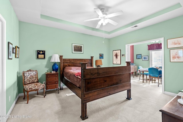 bedroom featuring a tray ceiling, baseboards, visible vents, and light carpet