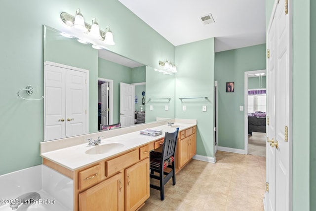 ensuite bathroom featuring visible vents, a sink, a bathing tub, double vanity, and baseboards