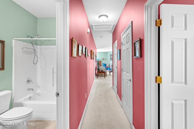 corridor featuring attic access, baseboards, and carpet floors