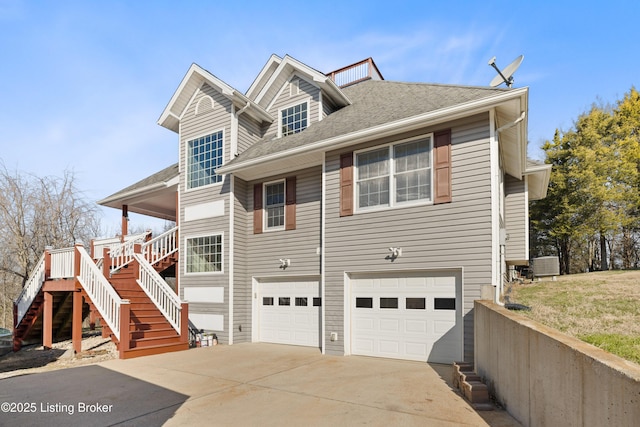 view of front of property with stairway, driveway, roof with shingles, an attached garage, and central AC