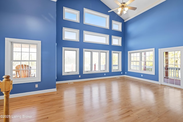 unfurnished living room featuring visible vents, wood finished floors, baseboards, and high vaulted ceiling