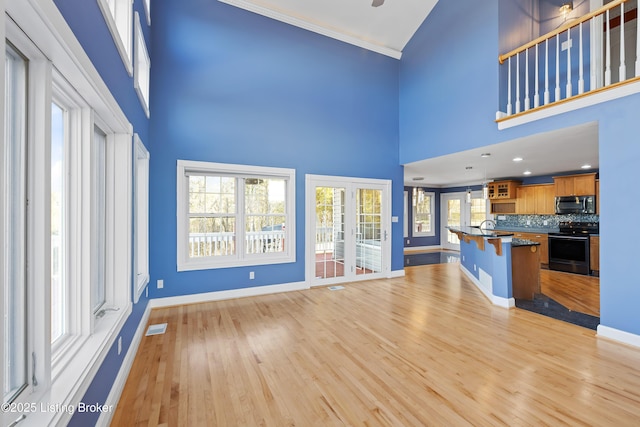 unfurnished living room featuring light wood-type flooring, visible vents, and baseboards