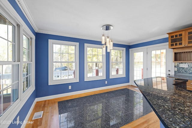 kitchen featuring visible vents, glass insert cabinets, crown molding, baseboards, and granite finish floor