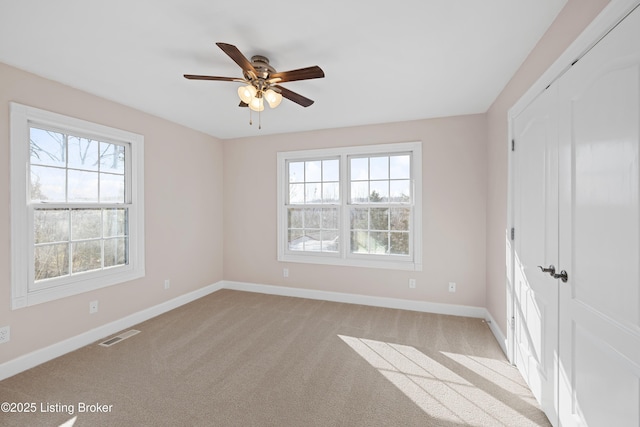 unfurnished bedroom featuring visible vents, multiple windows, and baseboards