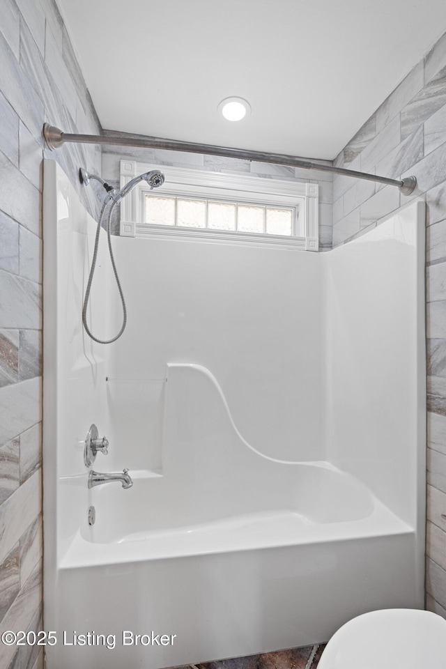 bathroom featuring shower / washtub combination and toilet