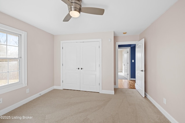 unfurnished bedroom featuring a closet, carpet flooring, multiple windows, and baseboards