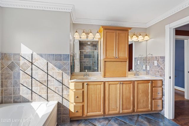 full bath with a sink, tile walls, ornamental molding, and a shower stall